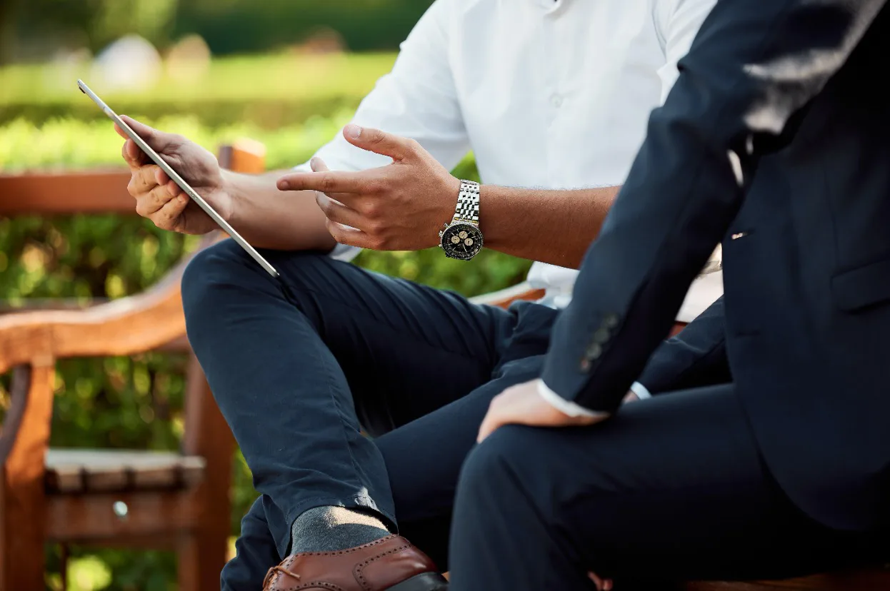 Two men dressed in business suits sitting on a bench, illustrating a moment of dialogue focused on transparency in their exchange.