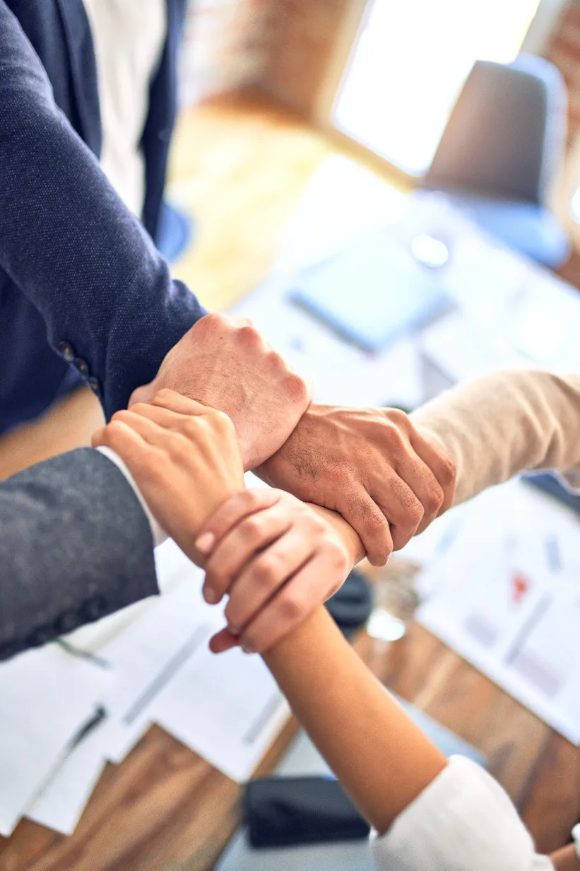 A group of business individuals demonstrating integrity by holding hands over a table