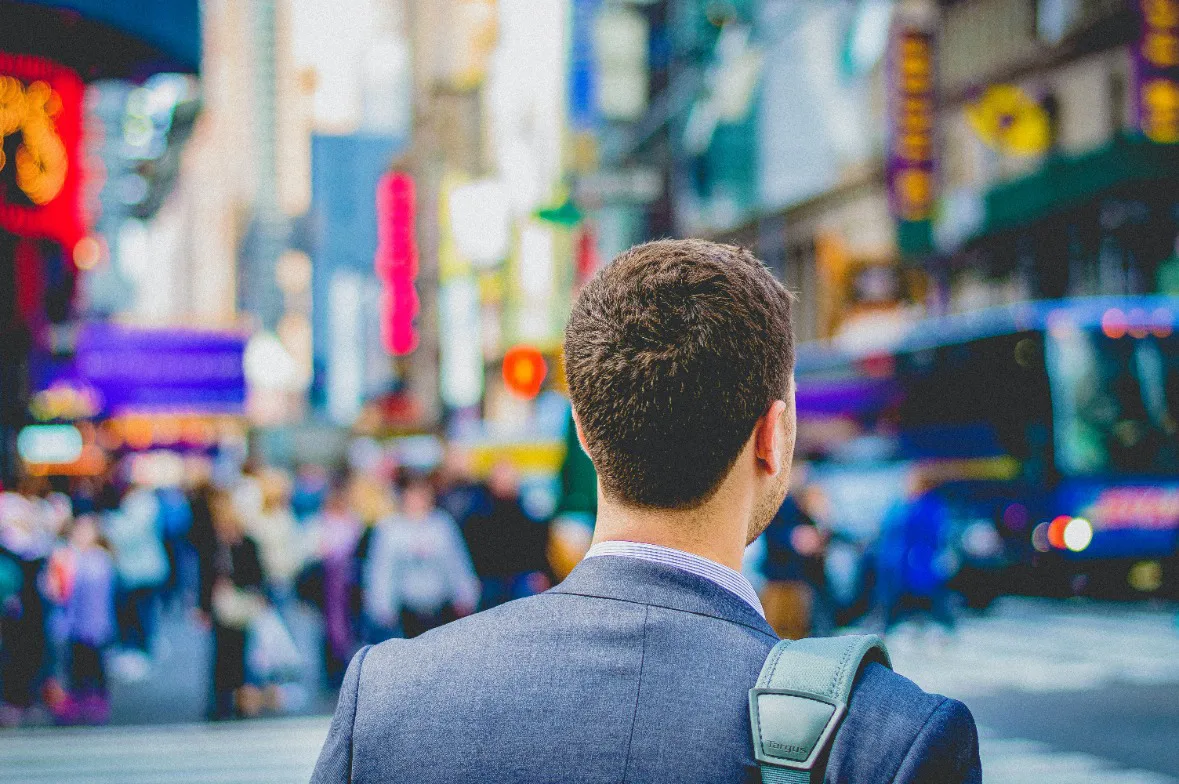  A man in a suit confidently walks down a bustling street