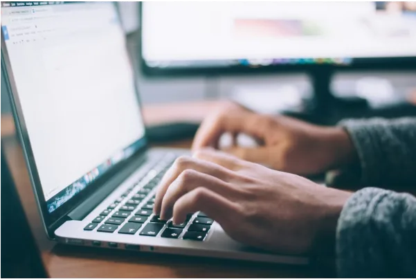 Individual engaged in typing on a laptop