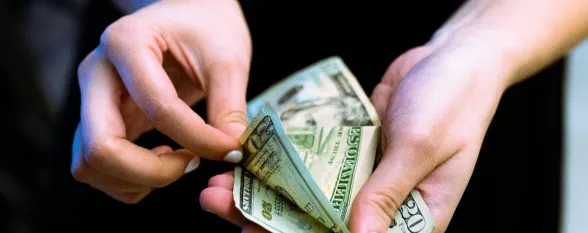 A person grips a substantial stack of currency